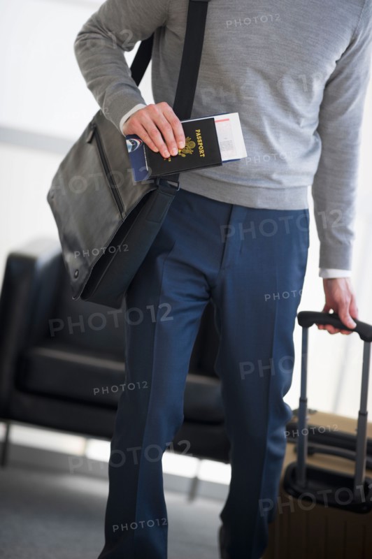 Businessman holding passport and suitcase.