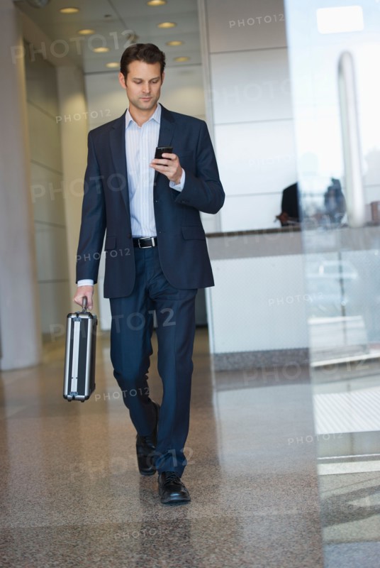 Businessman leaving office and using PDA.