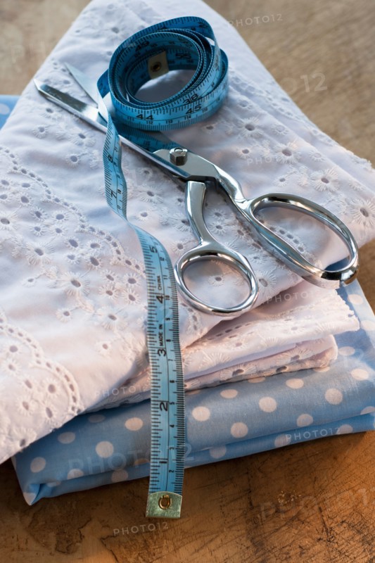 Close-up of folded textiles with scissors and tape measure.