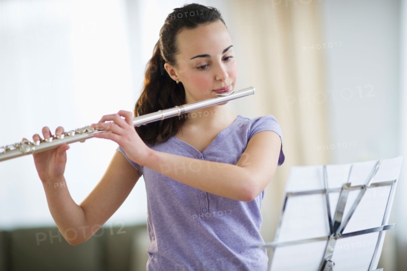Teenage girl (14-15) playing flute .