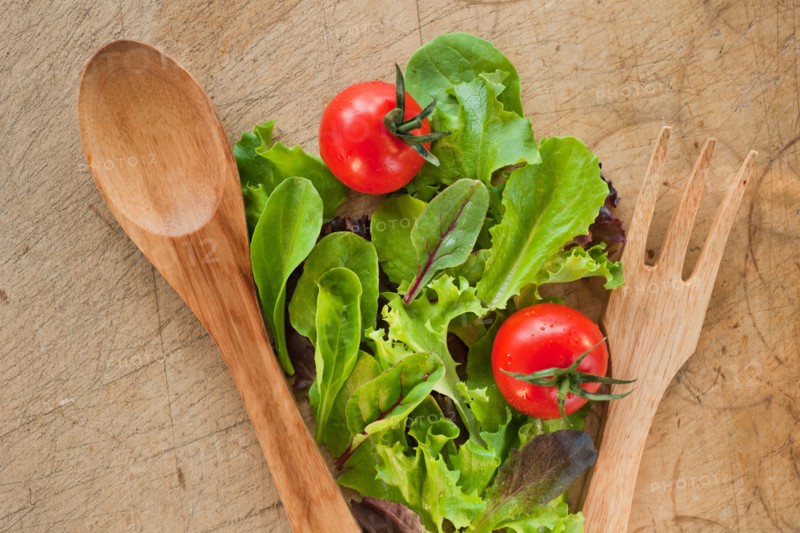 Salad leaves and wooden spoon and fork.