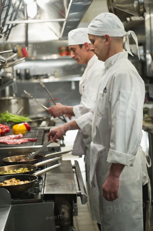 Chefs preparing food in kitchen.