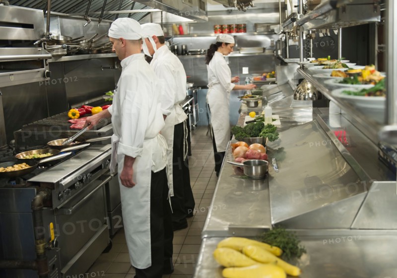 Chefs preparing food in kitchen.