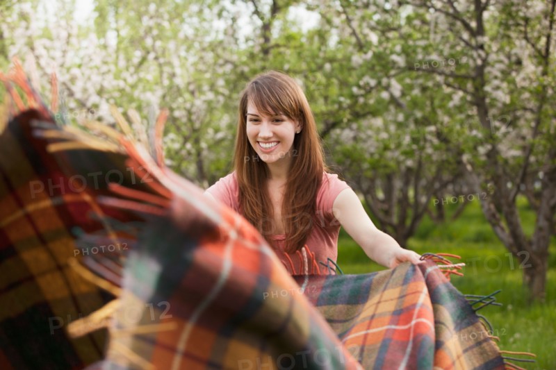 Young woman holding blanket in orchard. Photo : Mike Kemp