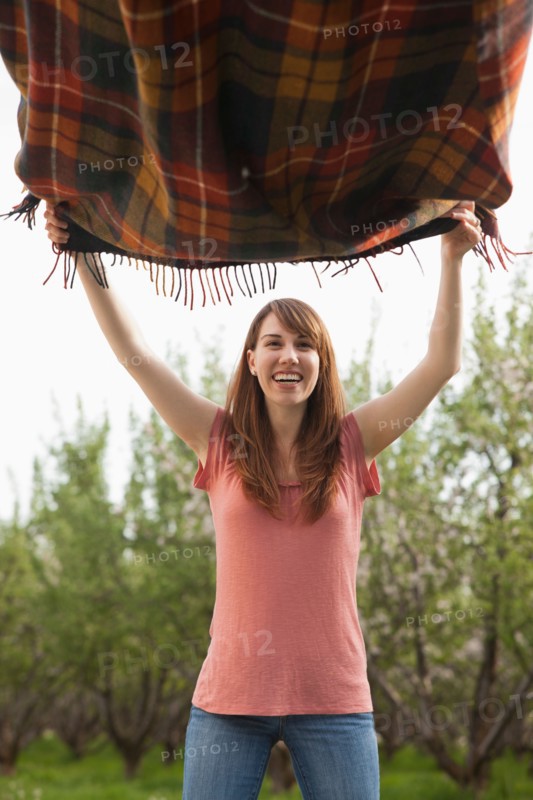 Young woman holding blanket in orchard. Photo : Mike Kemp