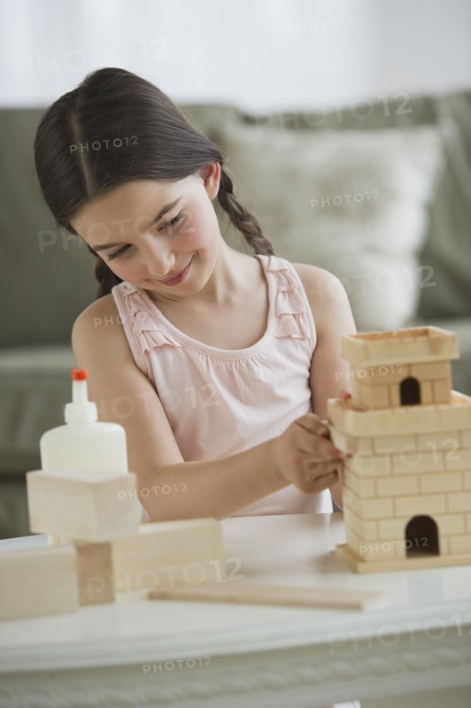Girl (8-9) building toy castle.