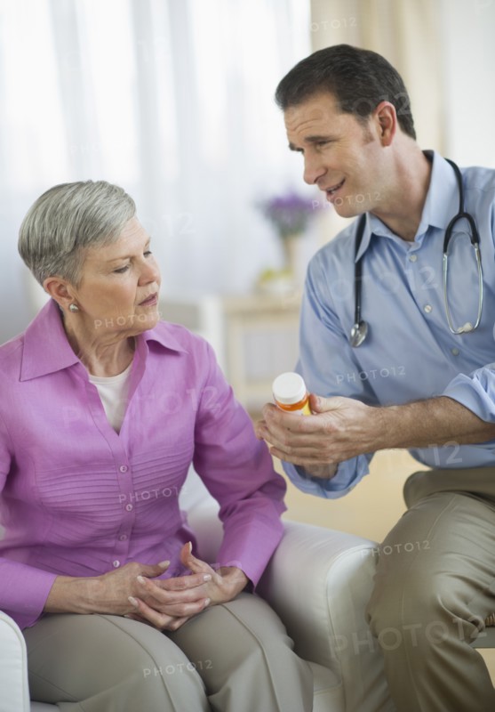 Smiling doctor giving medicine bottle to senior woman.
