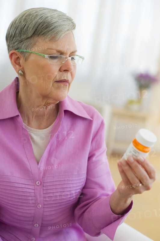 Senior woman looking at pill bottle.