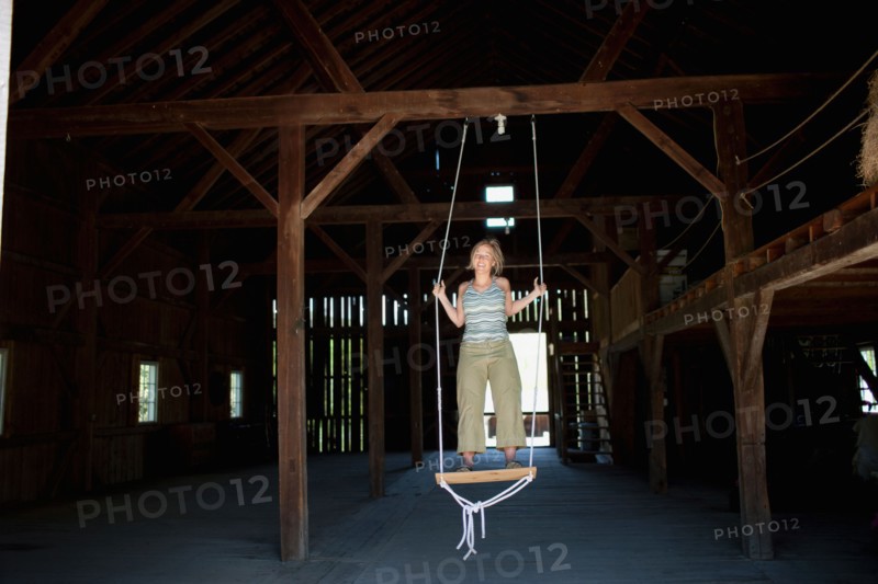 USA, Vermont, Dorset, Woman on swing in barn. Photo : Noah Clayton