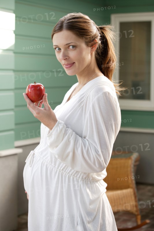 Portrait of expecting mother eating apple. Photo : Rob Lewine