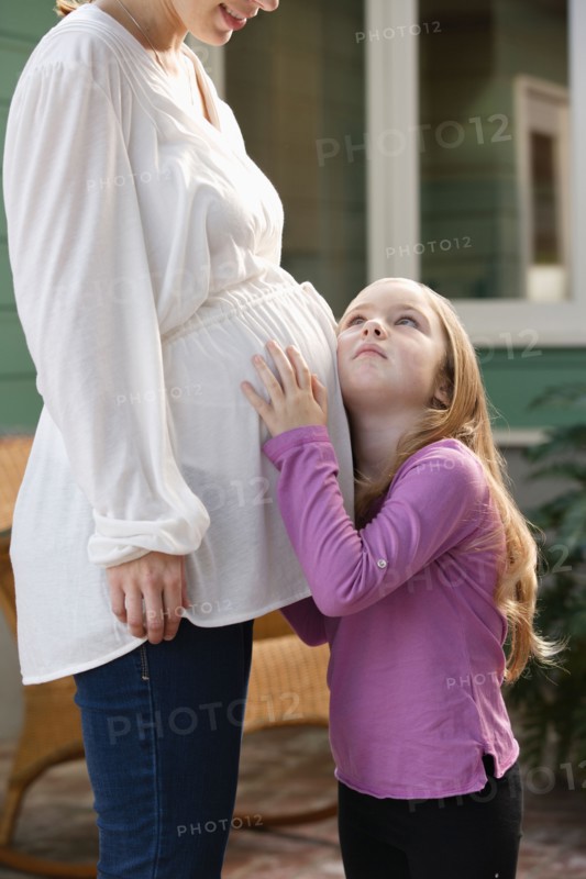 Girl (4-5) putting ear to expectant mother's belly. Photo : Rob Lewine