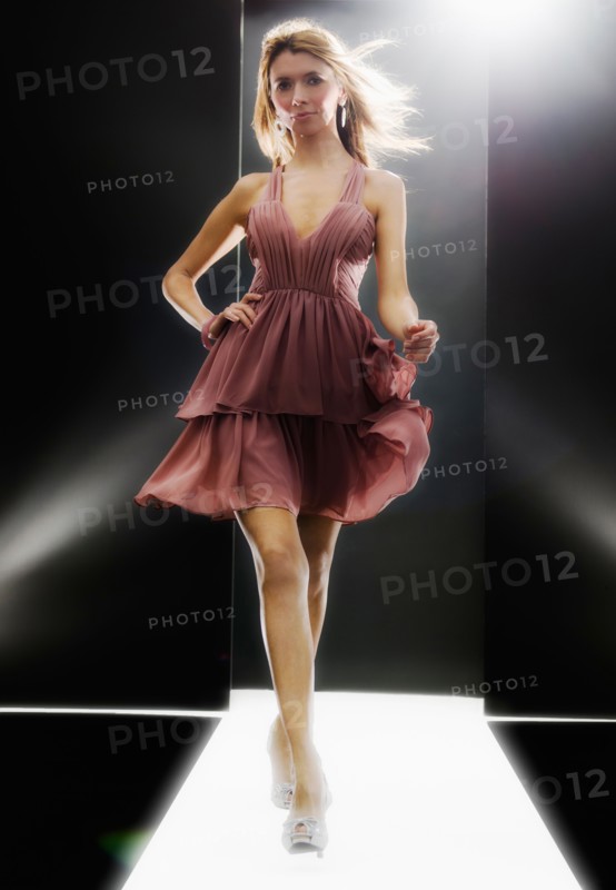 Female fashion model wearing dress on catwalk.