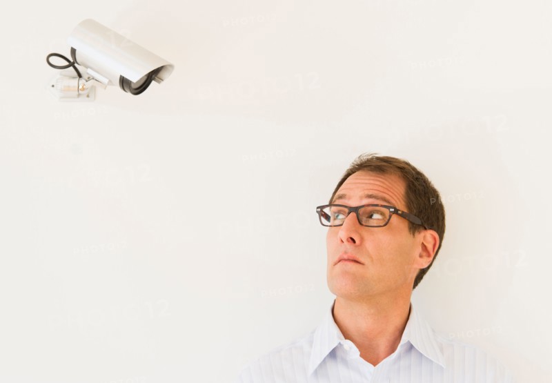 Businessman under surveillance of security camera.