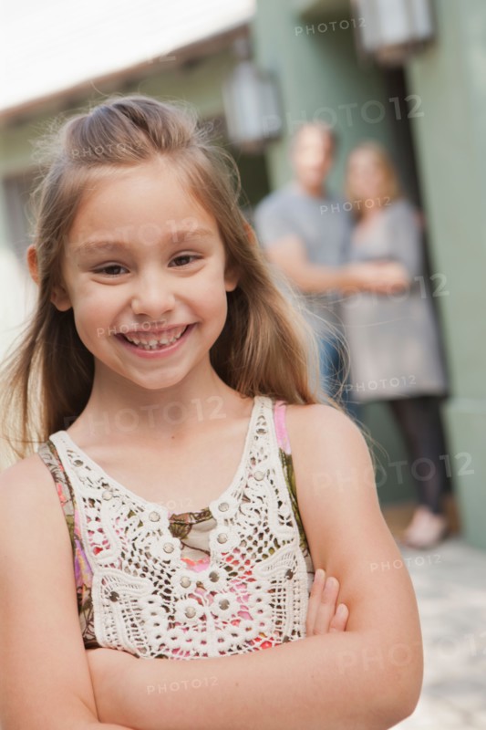 Portrait of cheerful girl (6-7) with parents in background. Photo : Rob Lewine