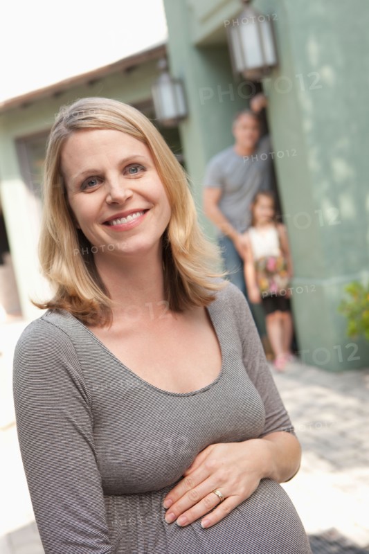 Portrait of pregnant mother with family in background. Photo : Rob Lewine