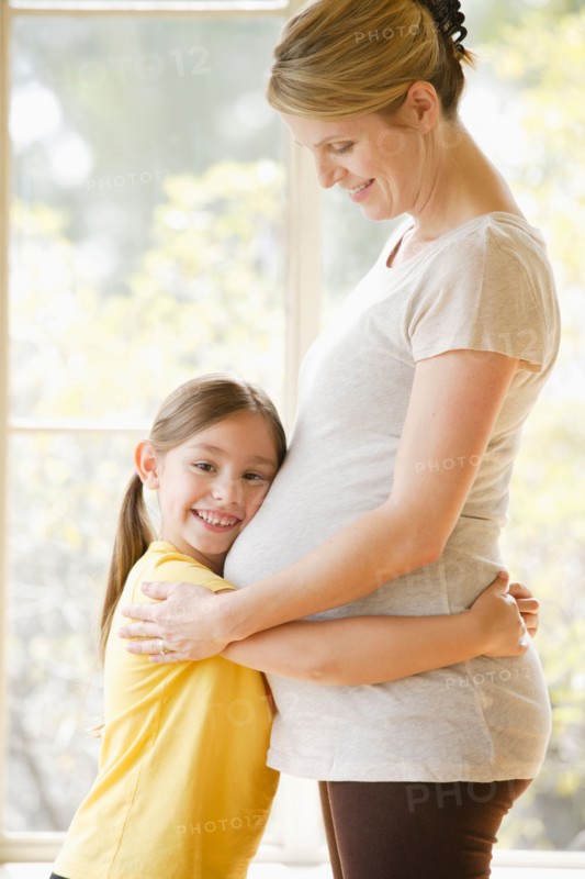 Daughter (6-7) embracing pregnant mother. Photo: Rob Lewine