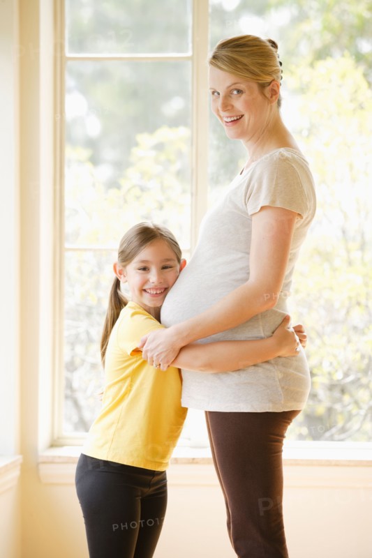 Daughter (6-7) embracing pregnant mother. Photo : Rob Lewine