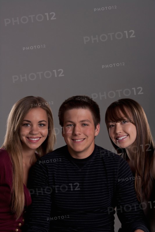 Portrait of teenage boy (16-17) and girl (16-17) with young friend, studio shot. Photo : Rob Lewine