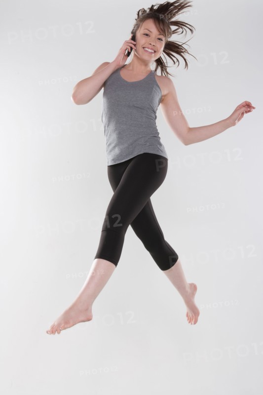 Portrait of young woman jumping, studio shot. Photo : Rob Lewine
