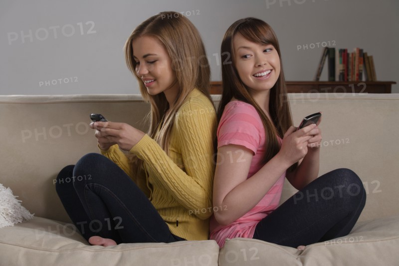 Portrait of teenage girl (16-17) with young woman sitting on sofa. Photo : Rob Lewine