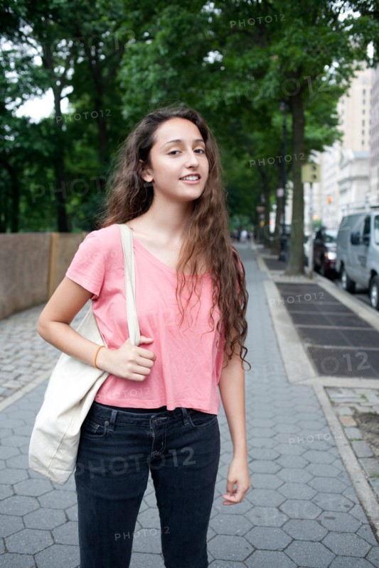 USA, New York, New York City, Portrait of smiling young woman standing on street. Photo: Winslow Productions