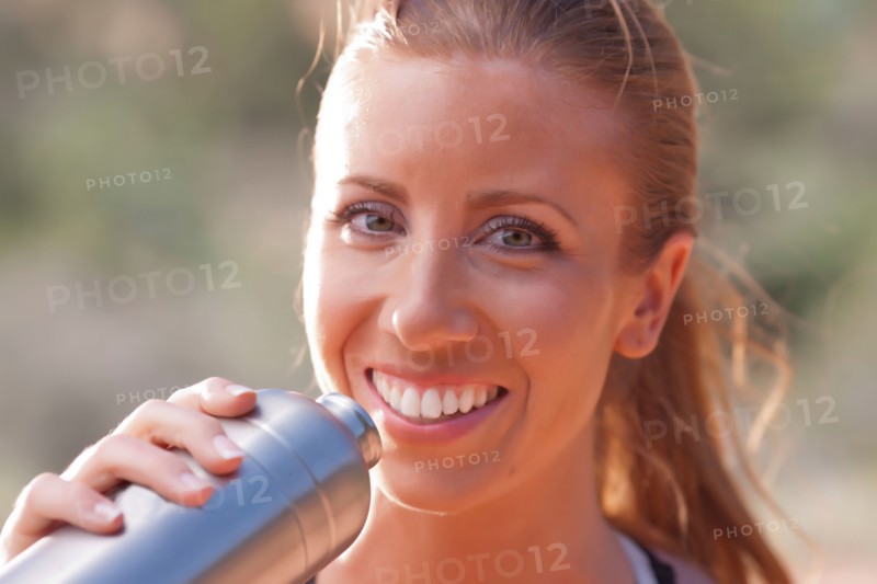 Smiling woman drinking water after jogging. Photo : db2stock