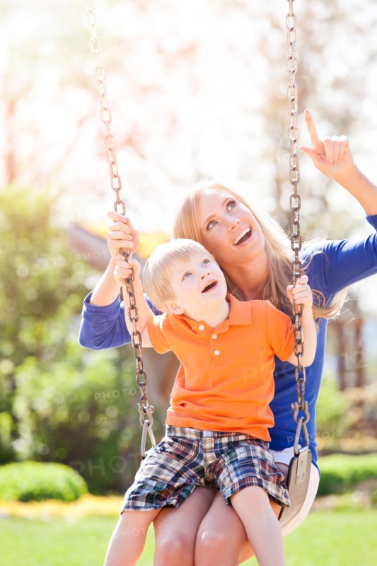 USA, Washington State, Seattle, Mother and son (2-3) swinging on swing in park. Photo : Take A Pix Media