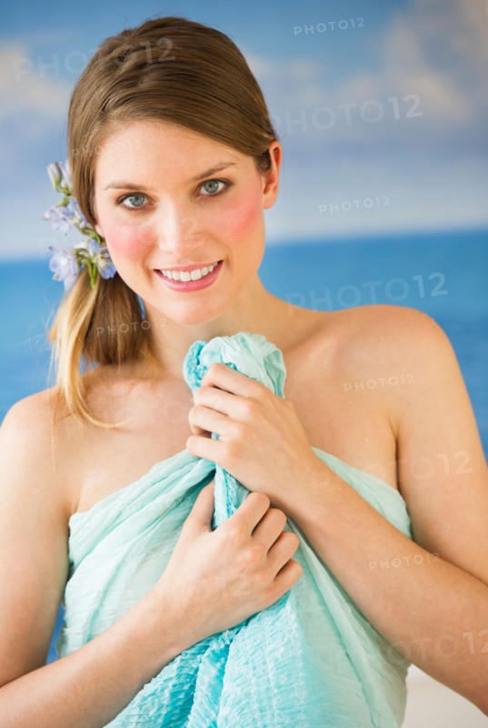 Portrait of young woman holding towel by sea.
