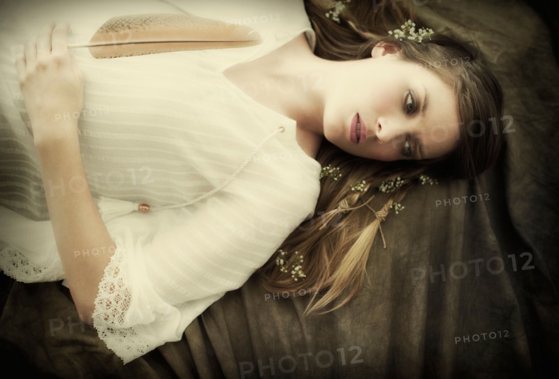 Young woman holding feather lying on back.