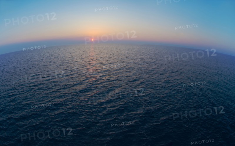 Aerial view of horizon over sea at sunrise.