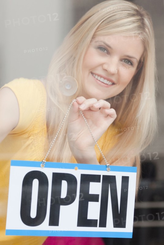 Portrait of young woman hanging sign in window. Photo: Jamie Grill