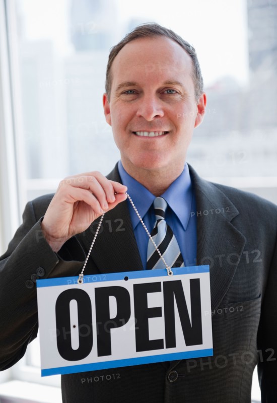 Businessman holding open sign. Photo : Jamie Grill