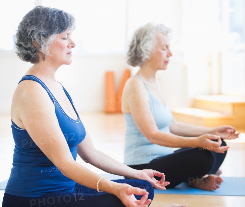 Two senior women practicing yoga. Photo : Daniel Grill