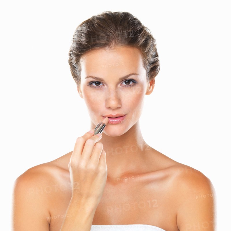 Studio portrait of beautiful woman applying lipstick. Photo : momentimages
