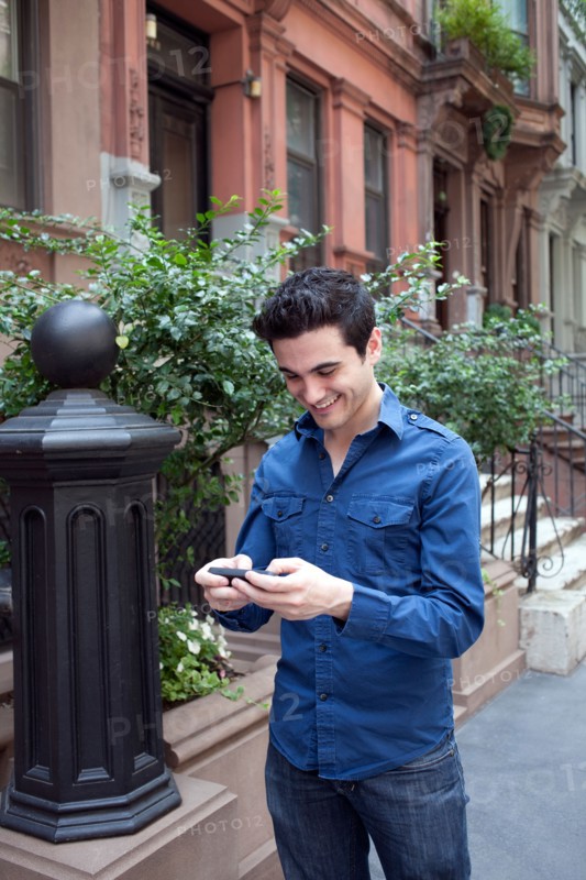 USA, New York, New York City, Young man texting on street. Photo : Winslow Productions