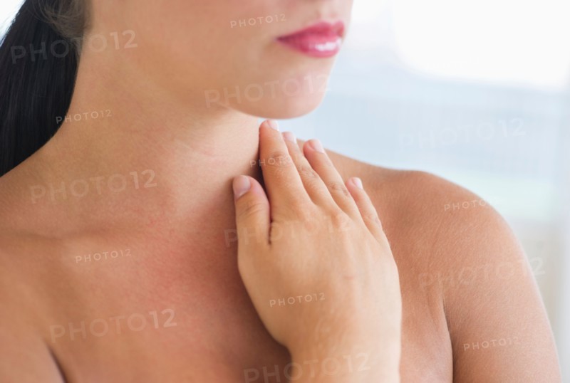 Young woman with hand on neck.