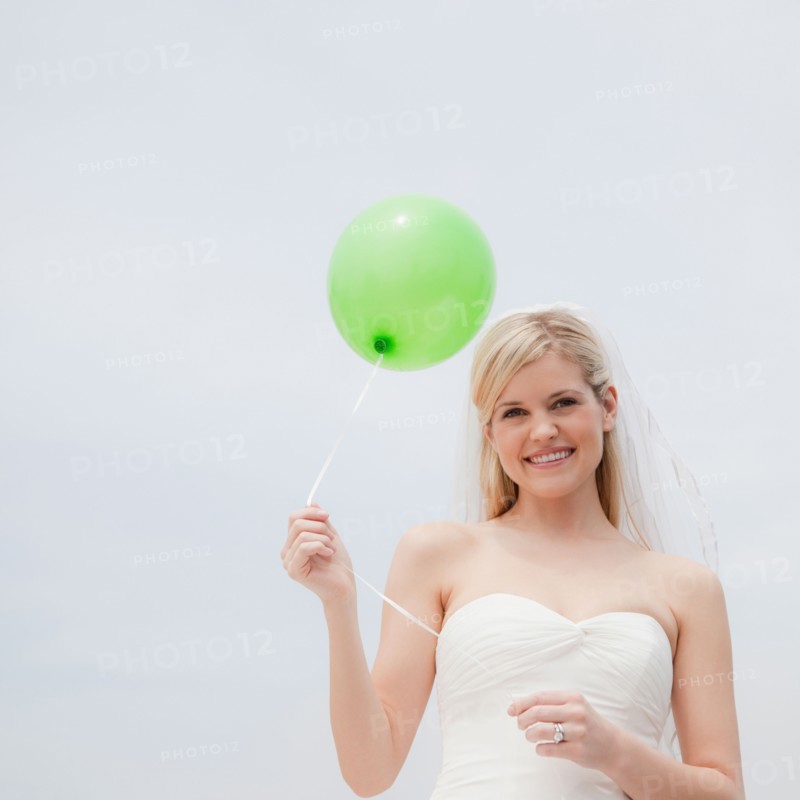 Happy bride holding green balloon. Photo : Jamie Grill