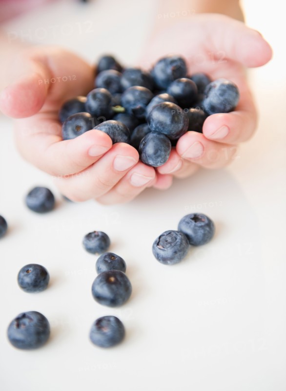 Close up of girl's (8-9) hands holding blueberries. Photo: Jamie Grill