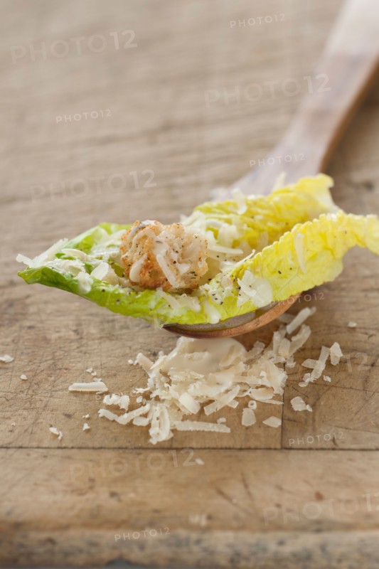 Fresh caesar salad on wooden spoon.