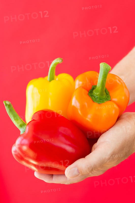 Hands holding bell peppers.