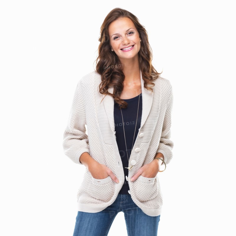 Studio shot of young woman with hands in pockets and smiling. Photo: momentimages
