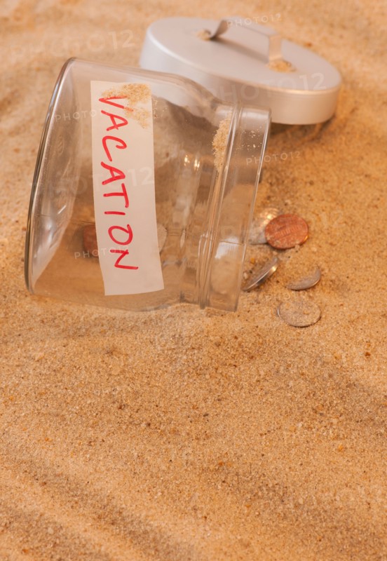 Close up of jar with coins spilled on sand. Photo: Daniel Grill