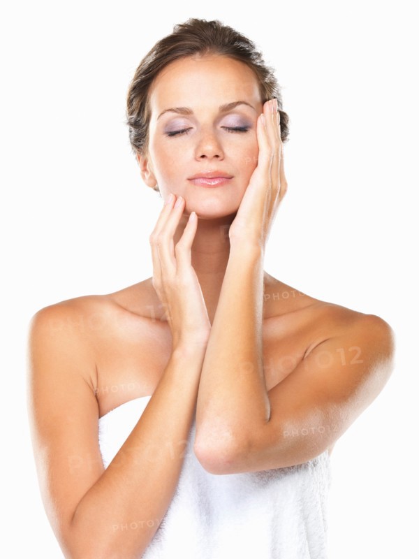 Studio portrait of beautiful woman wrapped in towel touching face. Photo: momentimages