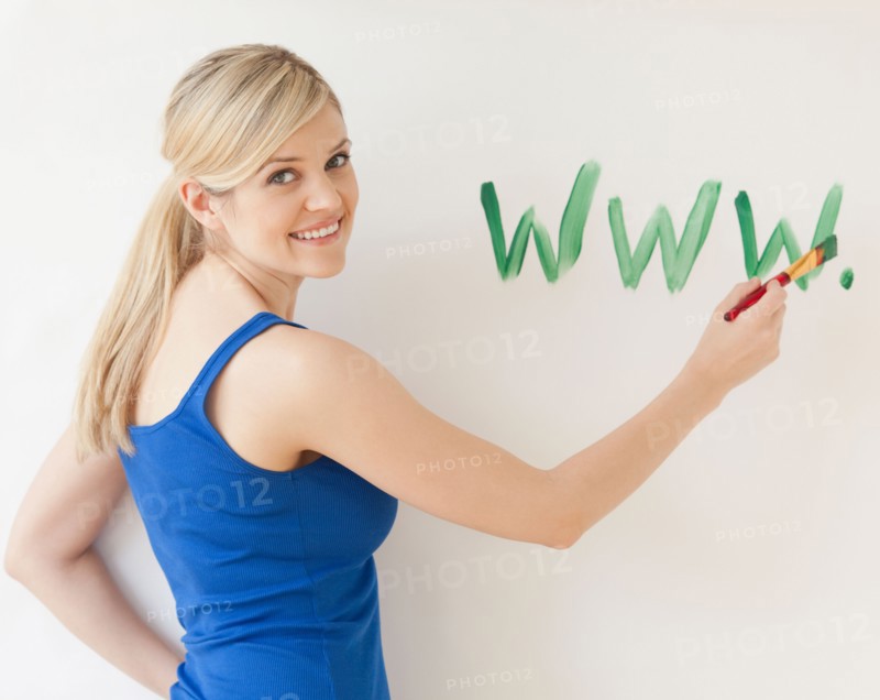 Blonde young woman writing web address on wall. Photo : Jamie Grill