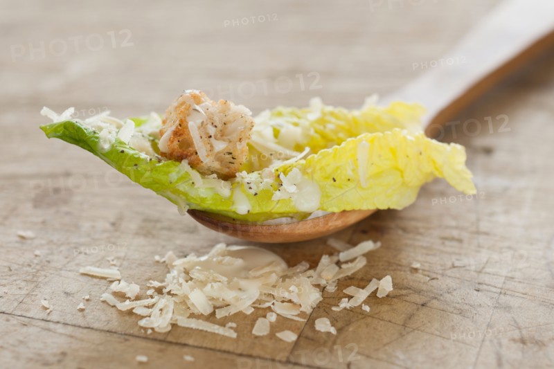 Fresh caesar salad on wooden spoon.
