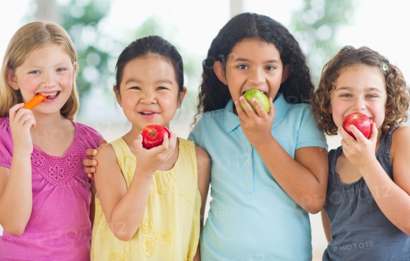 Portrait of girls (6-9) eating fruits.