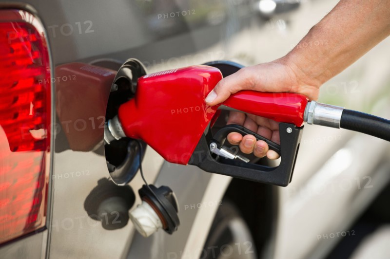 Hand holding fuel pump refueling car.