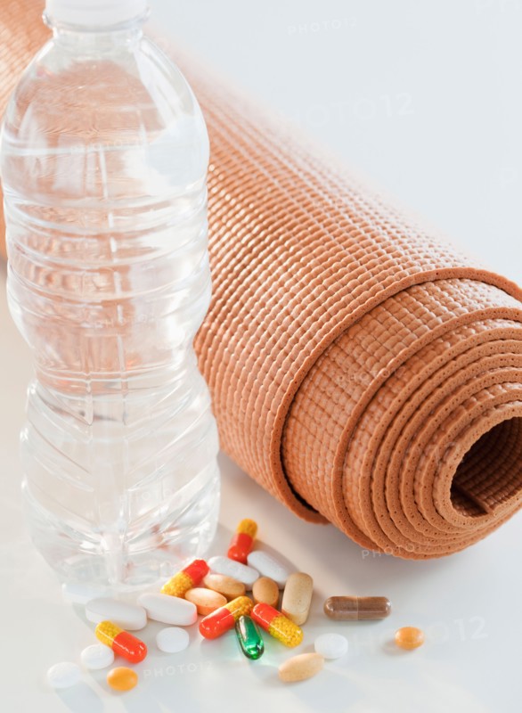Exercise mat, water bottle and colorful pills, studio shot. Photo : Jamie Grill