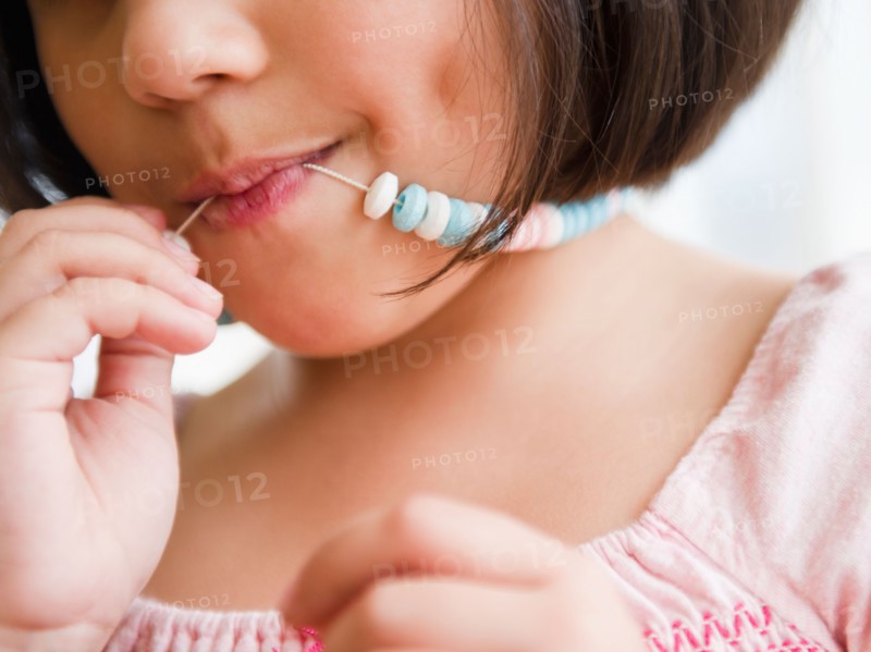 Close up of girl (8-9) with candy necklace. Photo : Jamie Grill