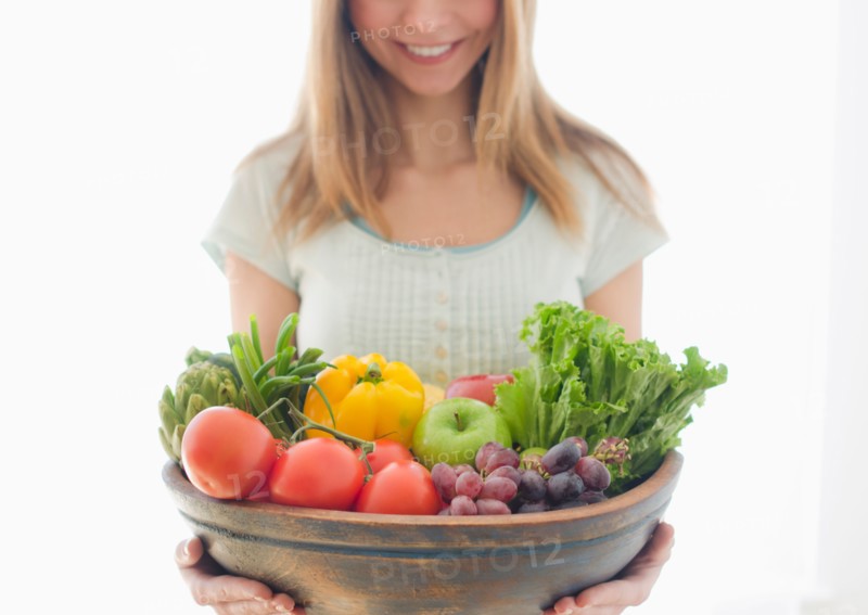 Woman holding bowl of organic fruit and vegetables.